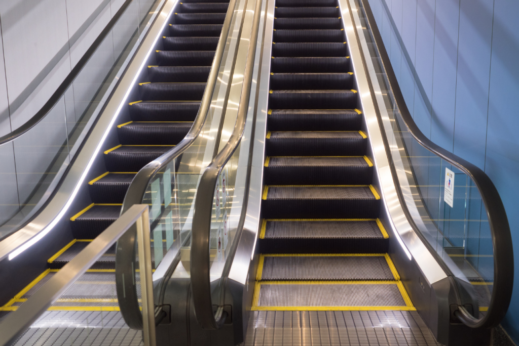 Eine Rolltreppe mit gelben Sicherheitslinien in einem Gebäude.