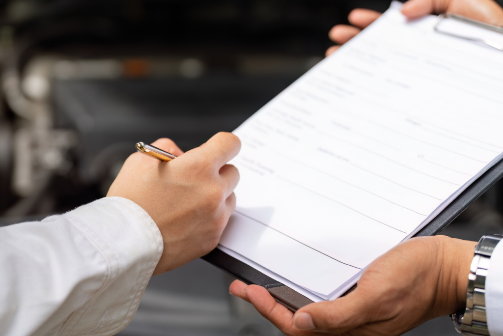 Eine Person schreibt auf ein Formular oder eine Checkliste auf einem Klemmbrett.