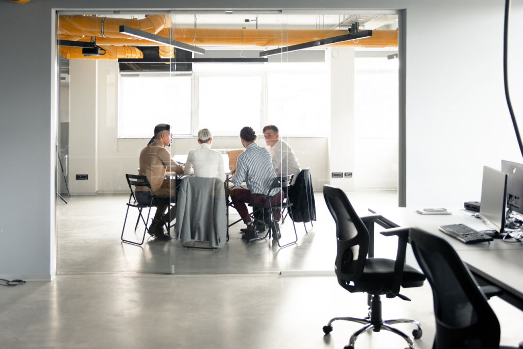 Eine kleine Gruppe von Menschen sitzt in einem modernen Büro bei einem Besprechungstisch.